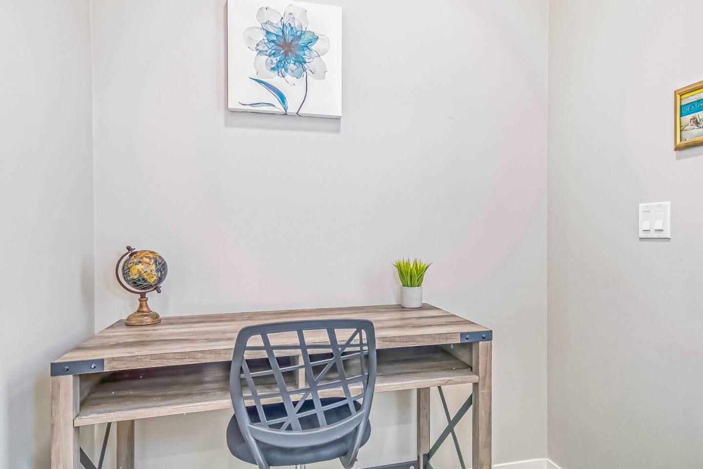A study area with a desk, chair, globe, and a framed picture on the wall.
