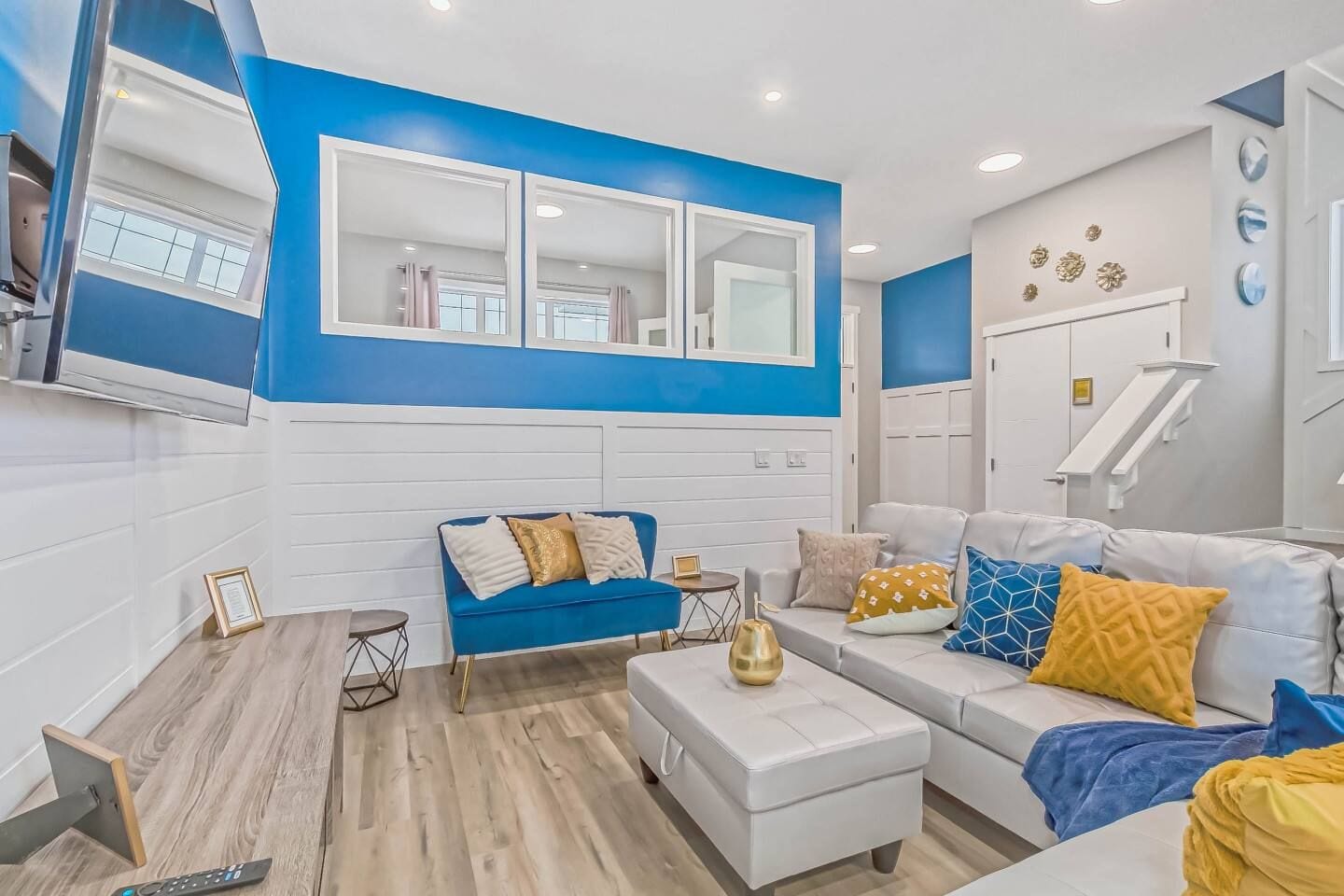 A modern living room with a blue accent wall, a white sofa, and a blue couch.