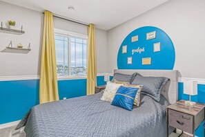 A bedroom with a bed, a nightstand, a window with curtains, and a wall with framed pictures. - ~XtraLargePrivateFencedYard|BBQ|AC|2FamilyRooms (Calgary)