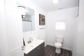 A bathroom with a white sink, dark wooden cabinets, a white toilet, and a shower curtain.