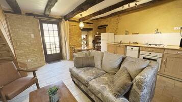A cozy living room with a patterned sofa, a wooden coffee table, and a dining area with a table and chairs.