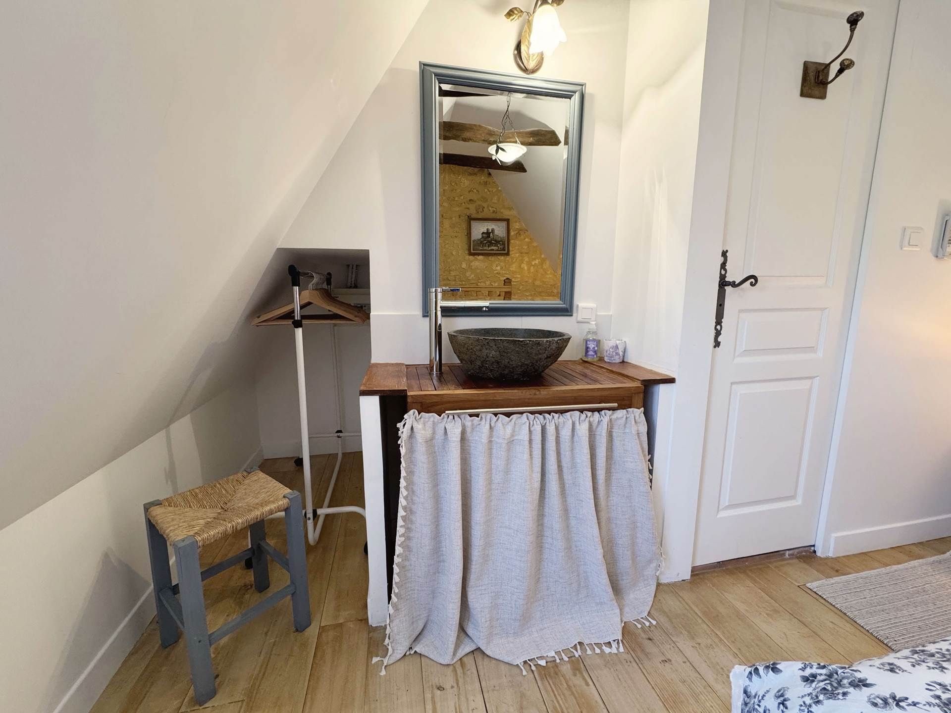 A bathroom with a wooden vanity, a large mirror, a hanging light fixture, and a towel rack.