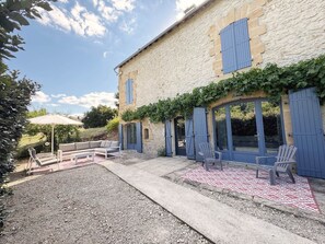 A stone building with blue shutters, outdoor seating, and a gravel patio. - La Violette – Spacious holiday home with private terrace and views (Meyrals)