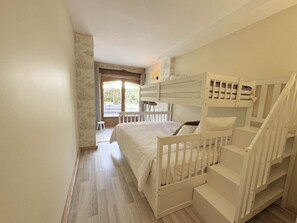 A bunk bed room with a window, a small stool, and a lamp. - La Violette – Spacious holiday home with private terrace and views (Meyrals)