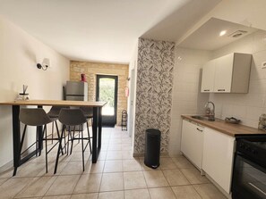 A compact kitchen with a dining area, a refrigerator, a sink, and a stove. - La Violette – Spacious holiday home with private terrace and views (Meyrals)