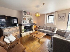 A cozy living room with a fireplace, a sofa set, a coffee table, and a television. - L’Anémone – Spacious holiday home for 8 people (Meyrals)