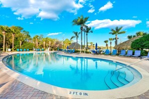 Una piscina con indicador de profundidad de 91 centímetros, rodeada de sillas de descanso y palmeras.
