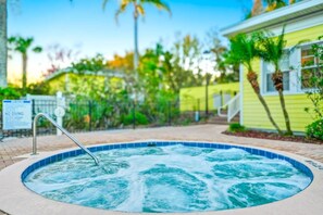 A hot tub with a metal railing, surrounded by a brick patio, palm trees, and a yellow building with white trim. - 2BR Bahama Bay Condo Near Disney (Davenport)