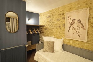 Een slaapkamer met een bed, een kapstok, een spiegel en een wanddecoratie van vogels.