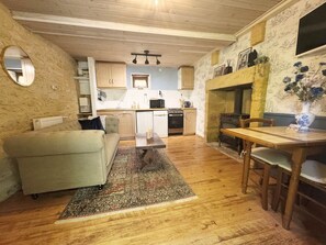 Una sala acogedora con un sofá, una mesa de comedor y una cocina al fondo.