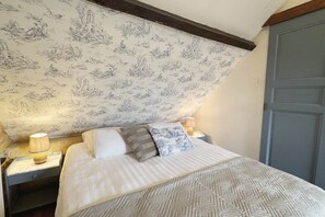 Ein Schlafzimmer mit einem Bett, Nachttischen, einer Lampe und einer Tür.