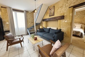 A modern living room with a sofa, armchairs, a coffee table, and a staircase leading to an upper level. - La Campanule – Spacious holiday home for 6 people with private hot tub (Meyrals)
