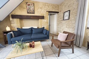 Ein gemütliches Wohnzimmer mit einem blauen Sofa, einem Holztisch und einem braunen Sessel.