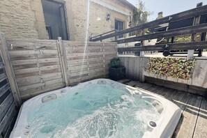 Een jacuzzi in een achtertuin met een houten schutting en een bloemenwand.