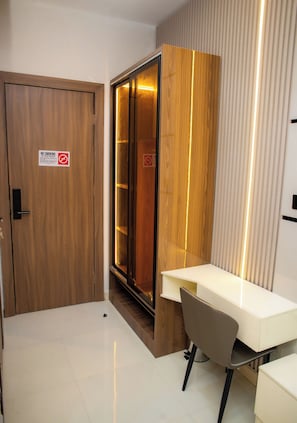 A hotel room with a wooden door, a sliding glass door, a white desk, and a chair. - Ellipse Hotels (Lagos)