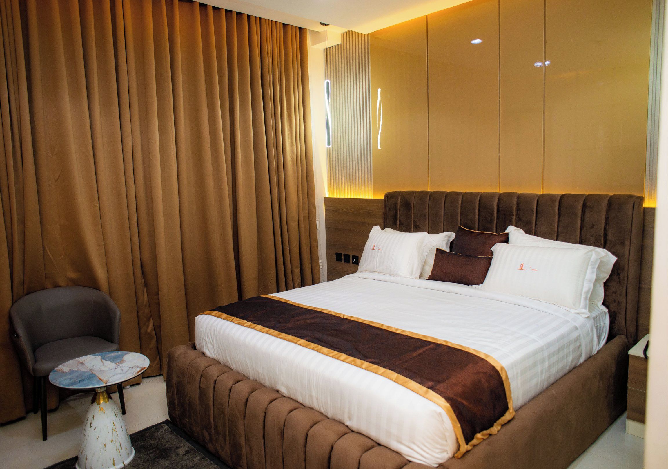 Una habitación de hotel con una cama grande, una silla y una mesita.
