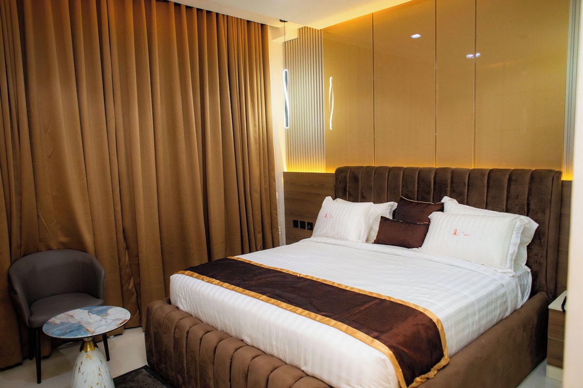 Una habitación de hotel con una cama grande, una silla y una mesita.