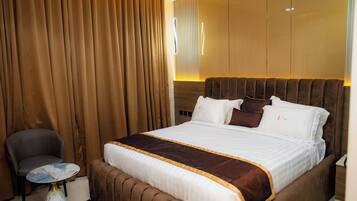 Una habitación de hotel con una cama grande, una silla y una mesita.