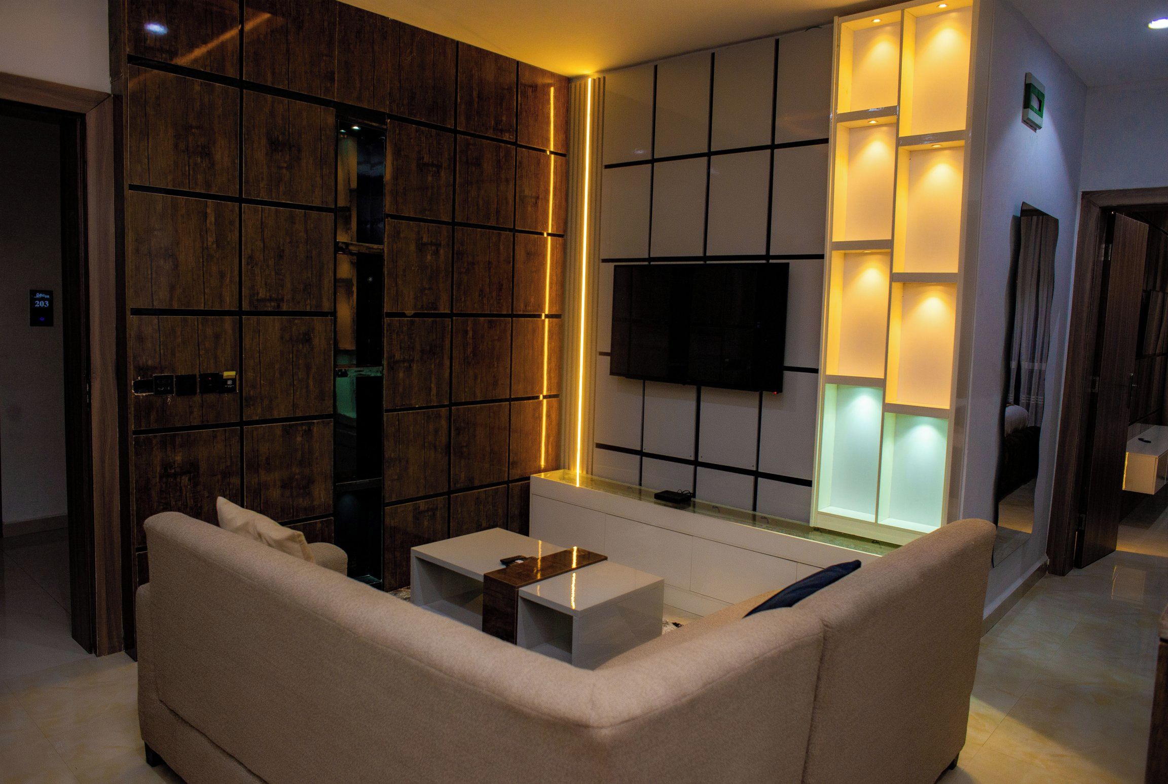 Una sala moderna con un sofá, una mesa de centro y un televisor de pantalla plana montado en la pared.