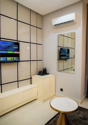 A modern bathroom with a tiled wall, a built-in toilet, a vanity with a mirror, and a round table with a marble top. - Ellipse Hotels (Lagos)