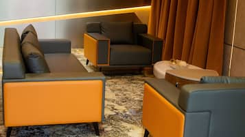 Una sala de estar moderna con un sofá, un sillón y un reposapiés, un piso de mármol y una lámpara de pared.