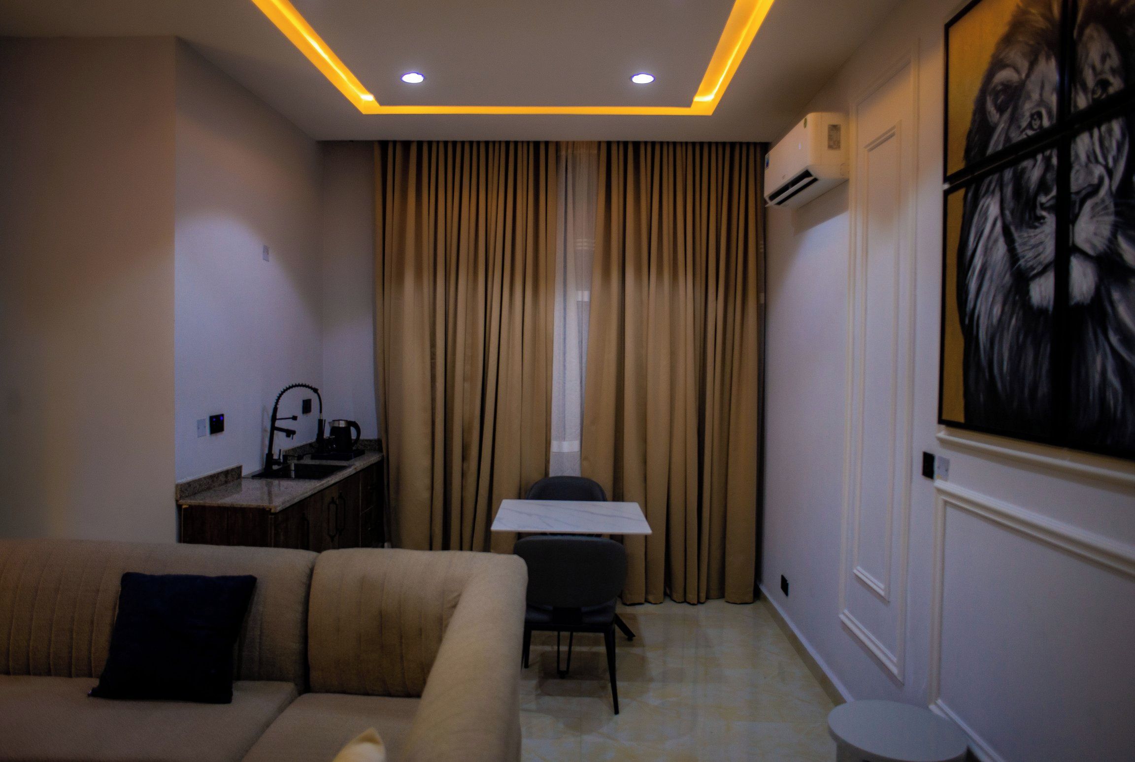 Habitación de hotel con sofá, mesa de comedor, una silla, una mesita redonda y un cuadro en la pared.