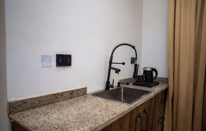 A compact kitchen with a granite countertop, a single sink, and a coffee maker. - Ellipse Hotels (Lagos)