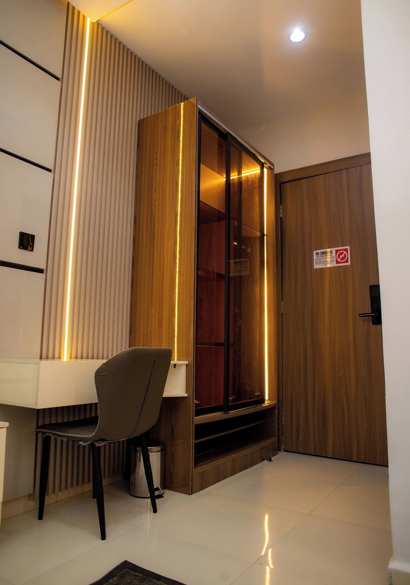 A modern room with a desk, chair, and a wooden cabinet with a glass door.