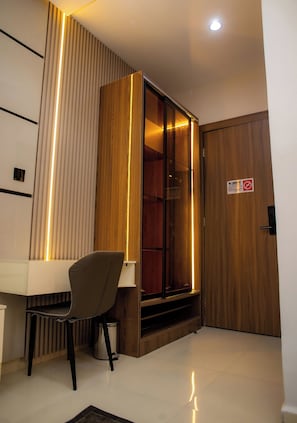 Una habitación moderna con escritorio, silla y un armario de madera con puerta de cristal.