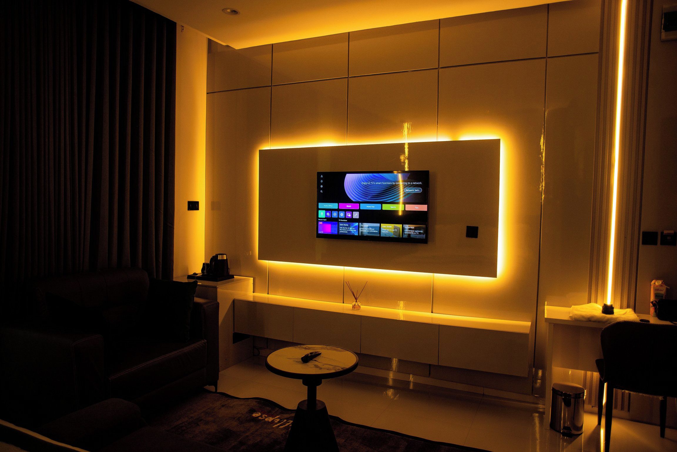 A modern living room with a flat-screen TV mounted on a wall, a coffee table, and a sofa.