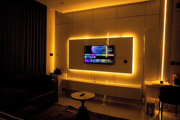 Una sala moderna con un televisor de pantalla plana montado en la pared, una mesa de centro y un sofá.