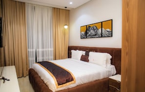 Una habitación de hotel con una cama grande, un televisor de pantalla plana y un cuadro en la pared.