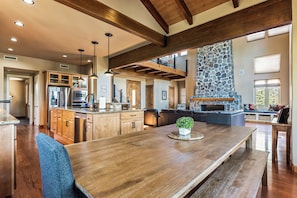 A spacious kitchen with wooden cabinets, a large island, and a stone fireplace. - Granite View Prescott Cabin - Hot Tub & Game Room Near Whiskey Row (Prescott)