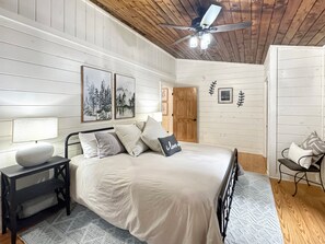 A bedroom with a bed, bedside table, lamp, and a ceiling fan. - Doe Run Hideaway - Pet Friendly | Hot Tub | Game Room | Firepit (Ellijay)