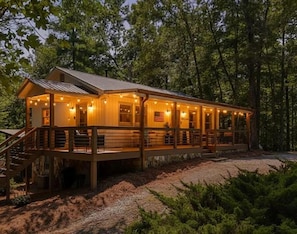 A wooden cabin with a covered porch, a staircase, and a gravel driveway. - Doe Run Hideaway - Pet Friendly | Hot Tub | Game Room | Firepit (Ellijay)