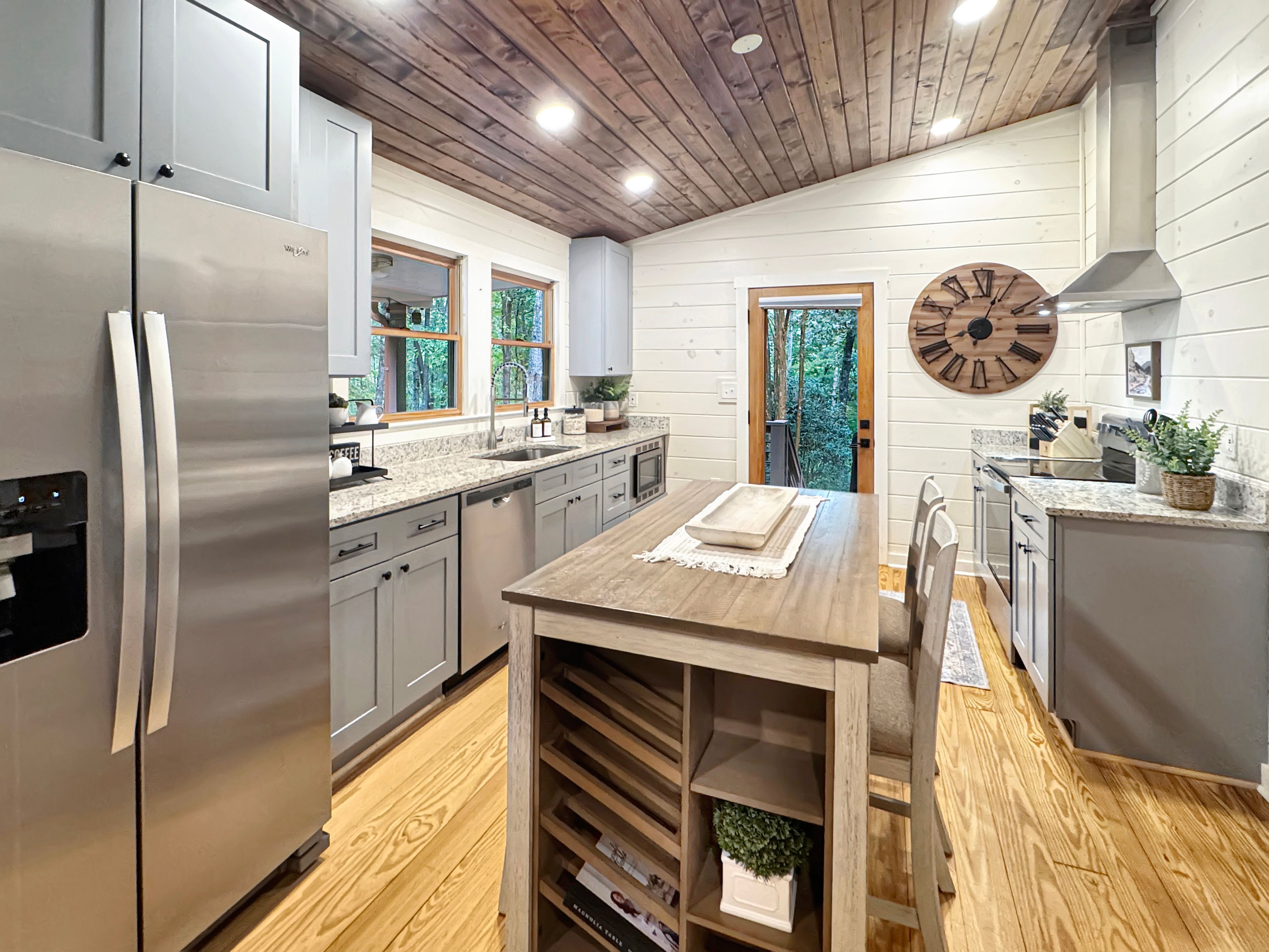 Une cuisine moderne dotée d’appareils électroménagers en acier inoxydable, d’un plancher en bois et d’un coin repas avec une table en bois.