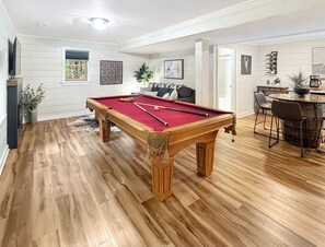A pool table in a room with wooden flooring, a sofa, and a coffee table. - Doe Run Hideaway - Pet Friendly | Hot Tub | Game Room | Firepit (Ellijay)