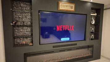 Eine moderne Unterhaltungswand mit einem Flachbildfernseher, der 'NETFLIX' anzeigt, und einem Kamin darunter.