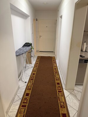 Ein Flur mit Teppich, einem Schreibtisch mit Laptop und einer Tür am Ende.