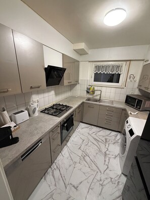 A modern kitchen with a gas stove, oven, microwave, and a built-in washing machine.