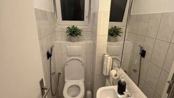 Ein kleines Badezimmer mit Toilette, Bidet, Waschbecken und Spiegel.