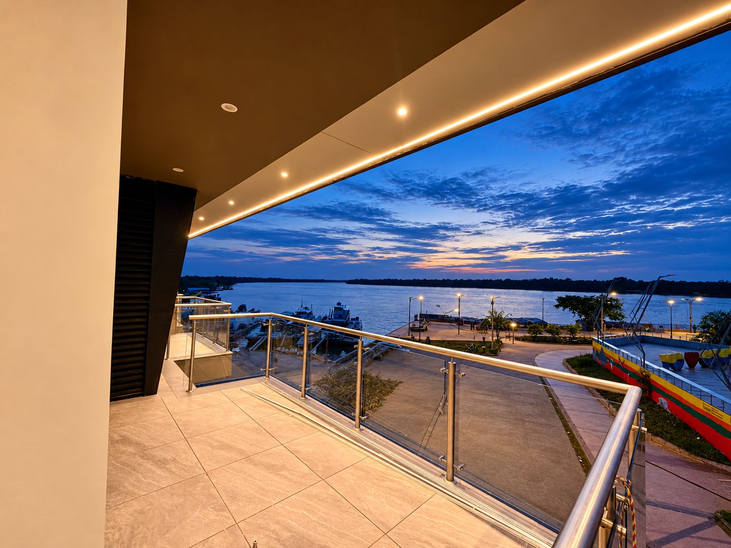 Een balkon met uitzicht op een jachthaven en een zonsondergang boven het water.
