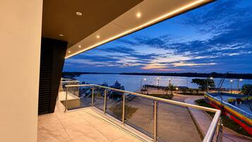 Een balkon met uitzicht op een jachthaven en een zonsondergang boven het water.