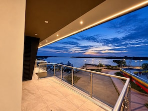 A balcony with a view of a marina and a sunset over the water.