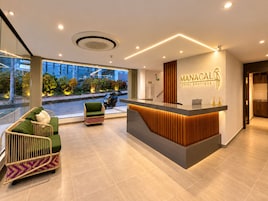 A hotel reception area with a modern design, including a reception desk, seating area, and large windows offering a view of the street.