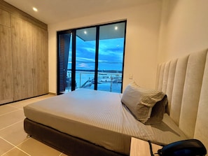 Un dormitorio con una cama grande, vista al agua y un armario de madera.
