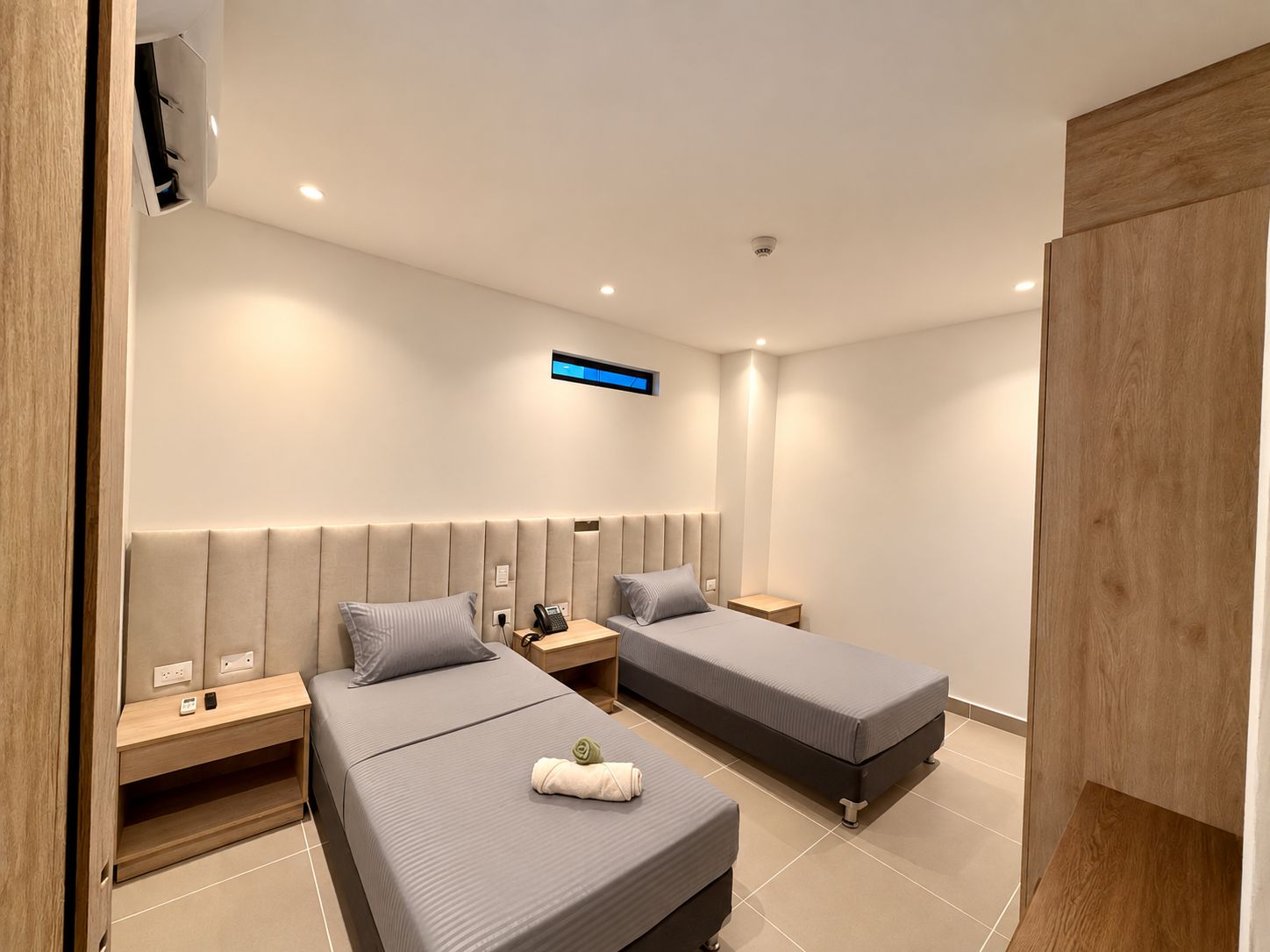Quarto de hotel moderno com duas camas, televisão de tela plana e aquecedor embutido.