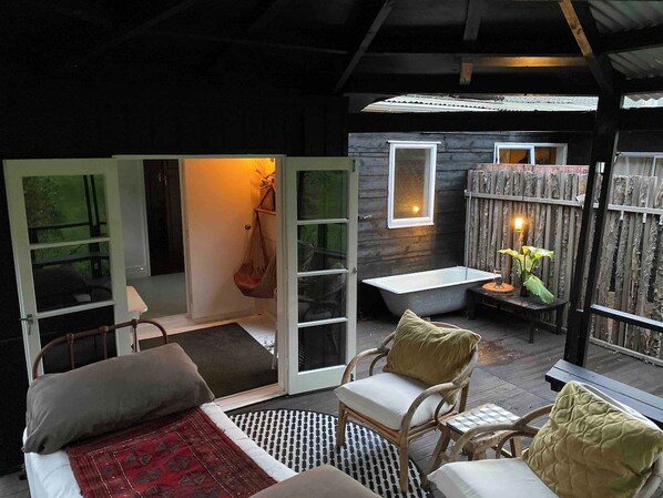 Une pièce confortable avec un lit, deux fauteuils, une petite table et une baignoire.