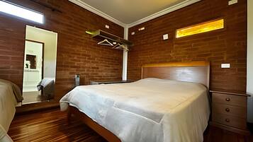 A bedroom with a wooden headboard, a bed with a white bedspread, a wooden dresser, and a mirror on the wall.