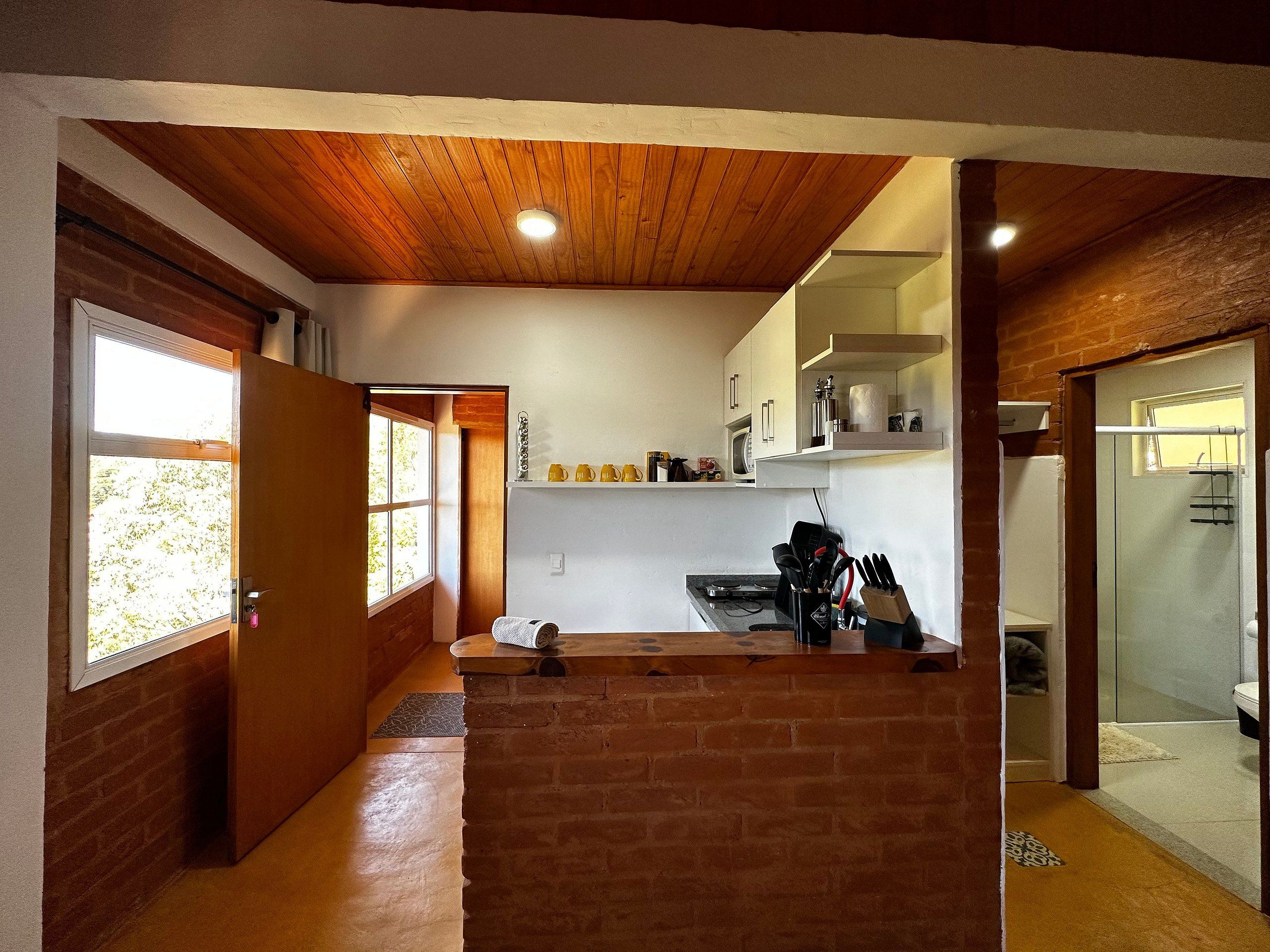 A compact kitchen with a wooden ceiling, a microwave, and a sink.